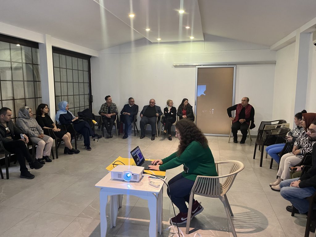 U düzeninde oturan otel işletmecileri ve bilgisayar başında oturarak eğitim vermekte olan erkek eğitmen