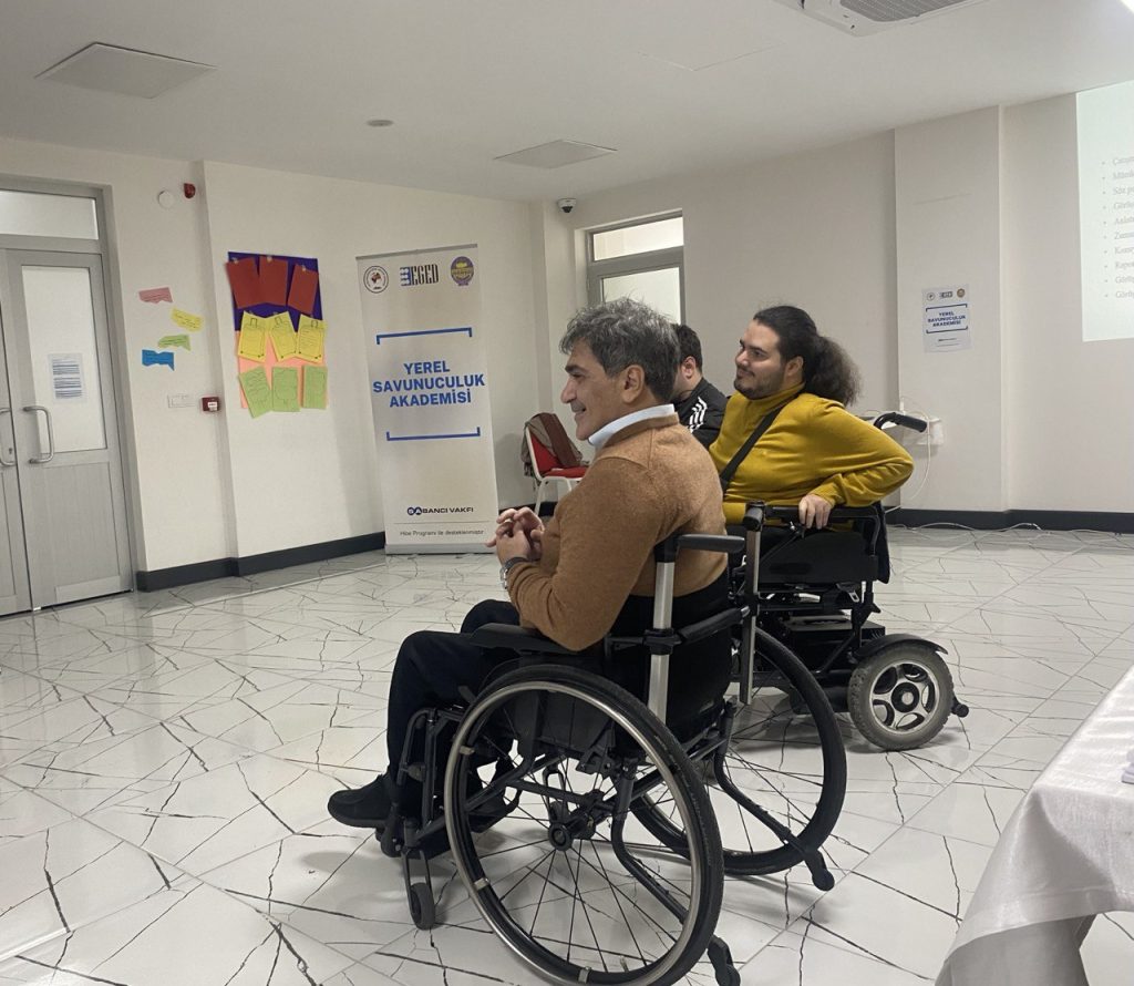 2 tane tekerlekli sandalye kullanan erkek birey aynı yöne bakıyorlar